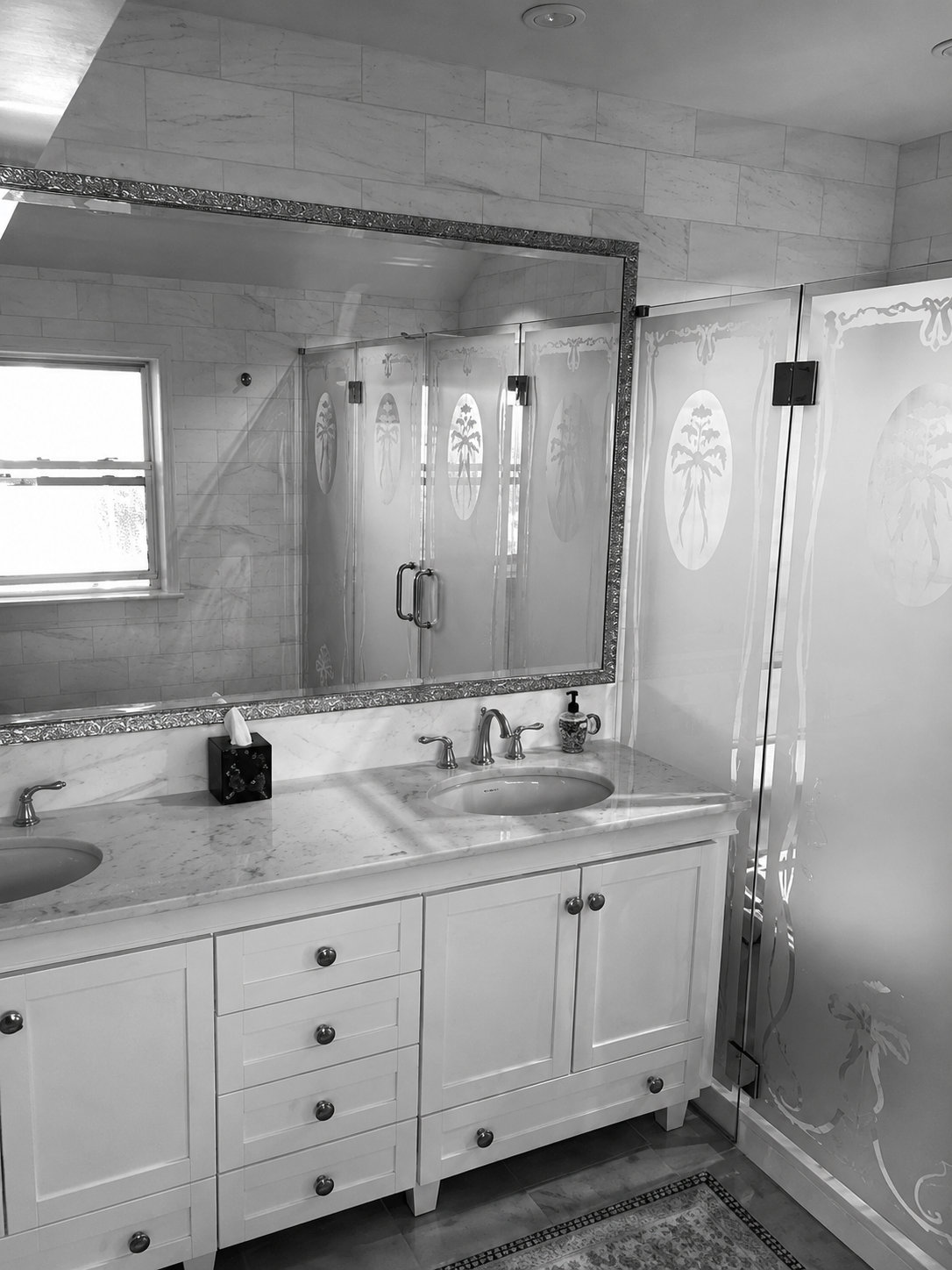 Black-and-white photo of a bathroom vanity, sink, mirror, and shower stall.
