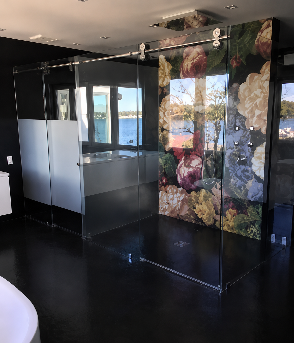 Modern interior with glossy black floor, glass partition, and colorful floral wall panels near windows.