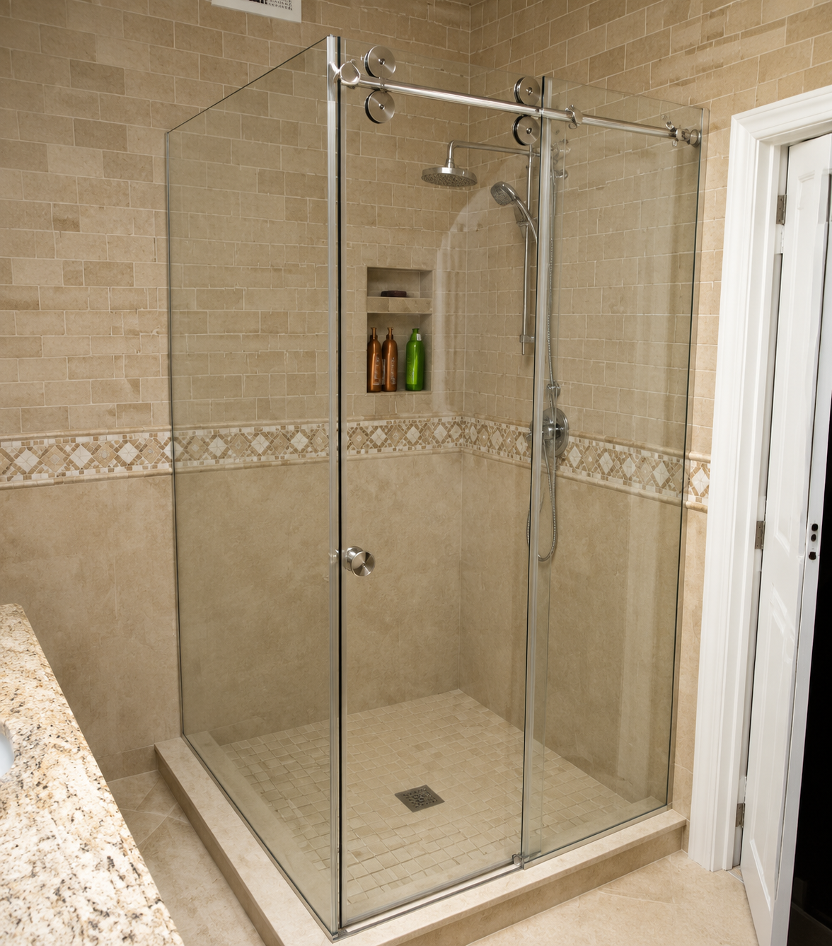 Glass-enclosed walk-in shower in a beige tiled bathroom with a built-in shelf and chrome fixtures