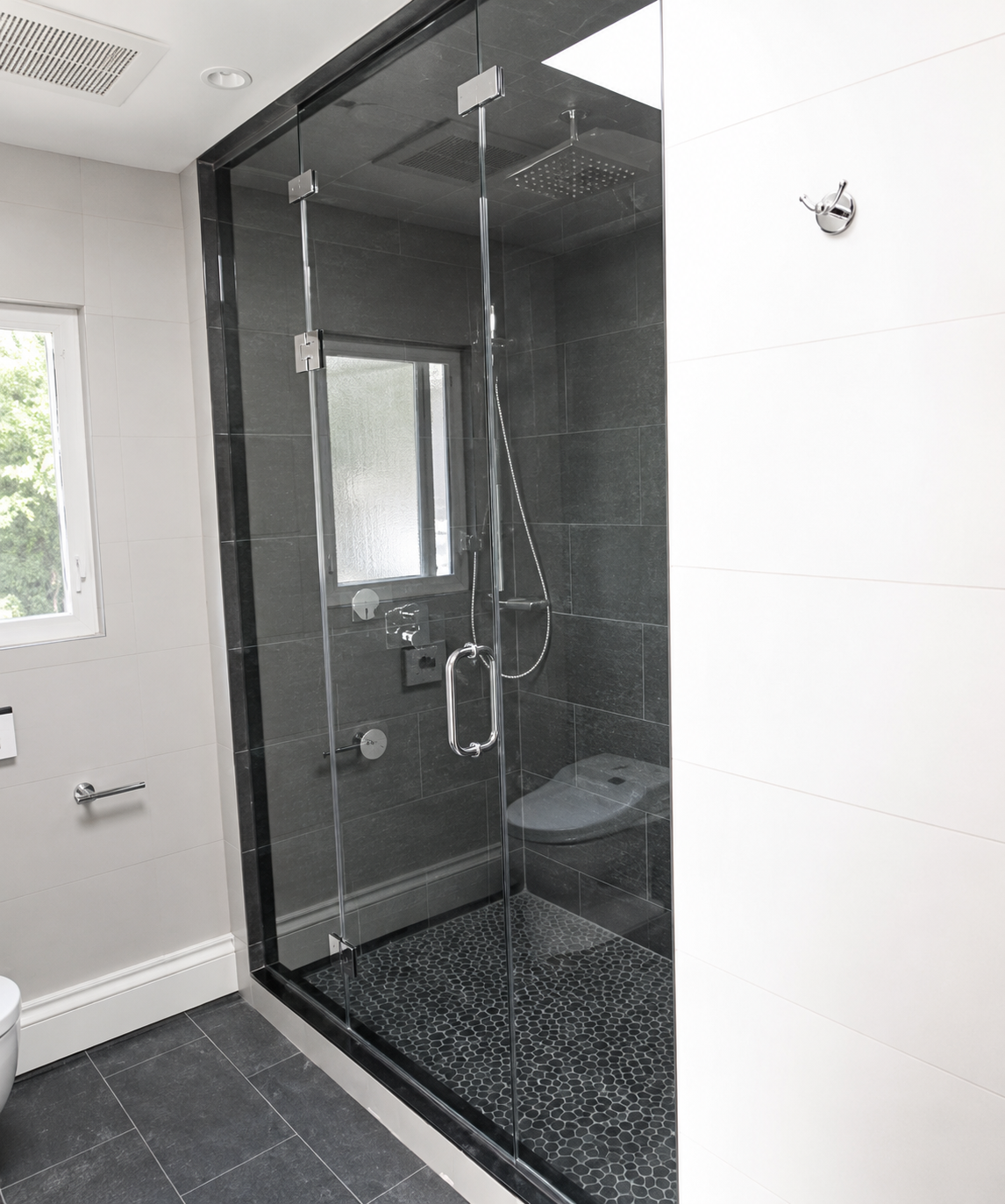 Modern bathroom with a glass-enclosed shower, dark tile floor, and white walls