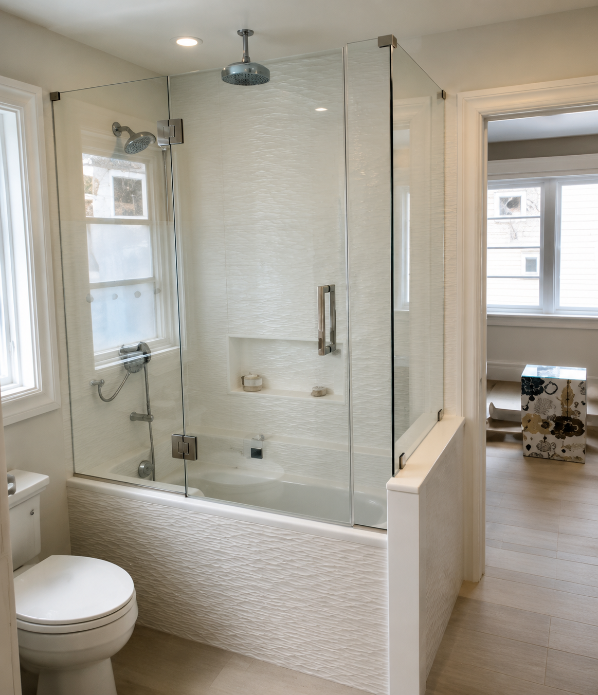 Bright bathroom with a glass-enclosed shower, white tile, and a toilet by the window.