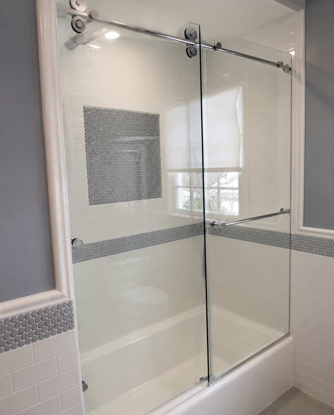 Glass shower enclosure with chrome hardware and white tiled bathroom walls