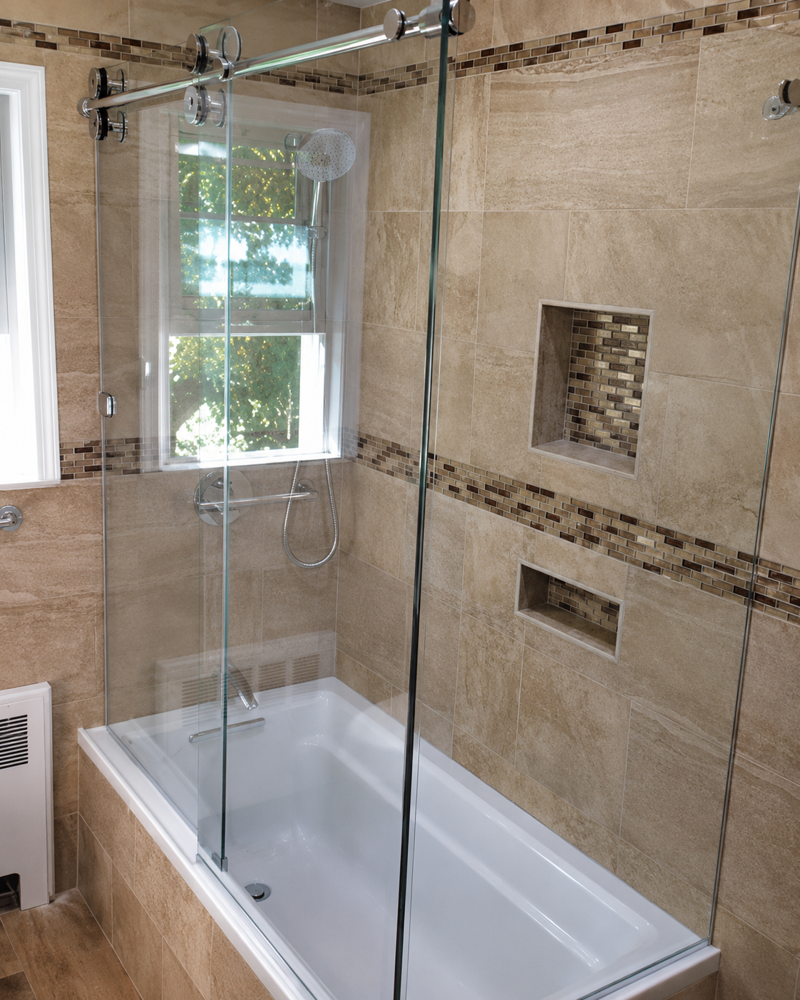 Glass-enclosed tiled bathtub shower with built-in wall niches and window light