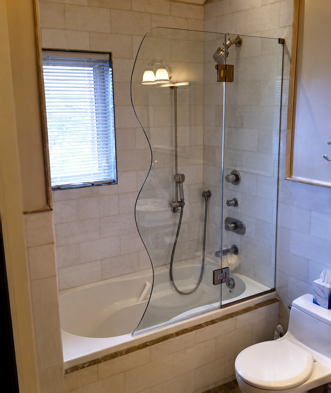 Bathroom with tiled walk-in tub, glass shower door, handheld showerhead, and toilet beside it.