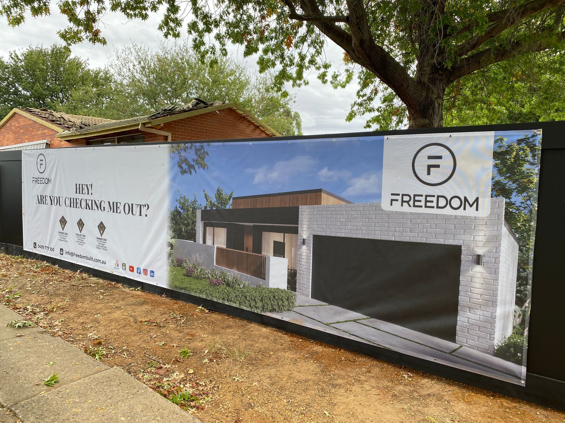 Banner on a fence promoting Freedom homes. Shows a house rendering and logo — Capital Signs in Fyshwick, ACT