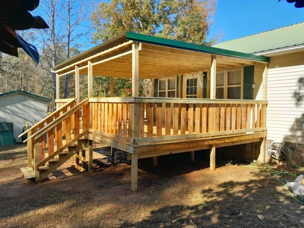Wooden deck with stairs and covered porch, attached to a house.