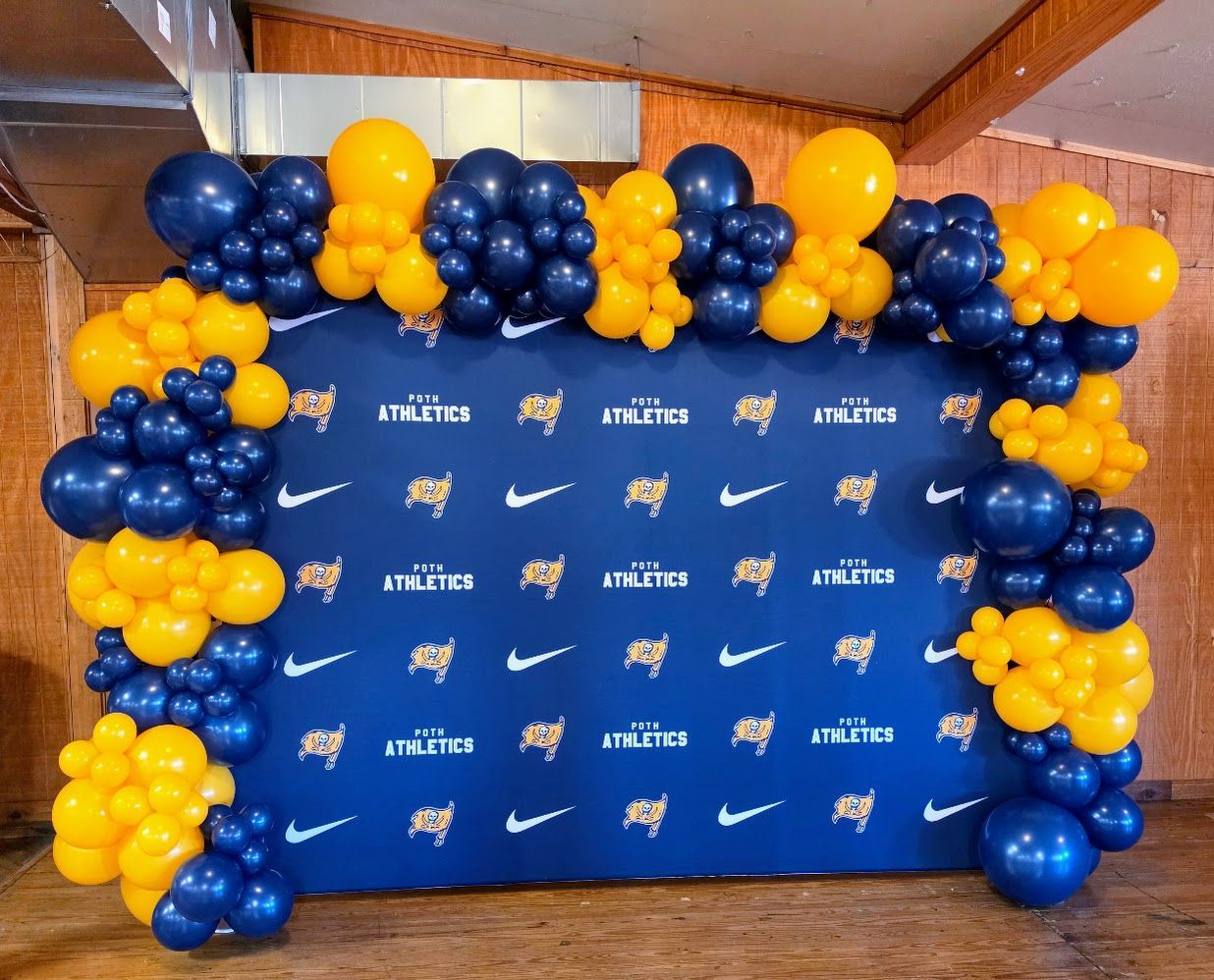 Custom navy and yellow organic balloon garland backdrop rental for event decor in Poth and South Texas