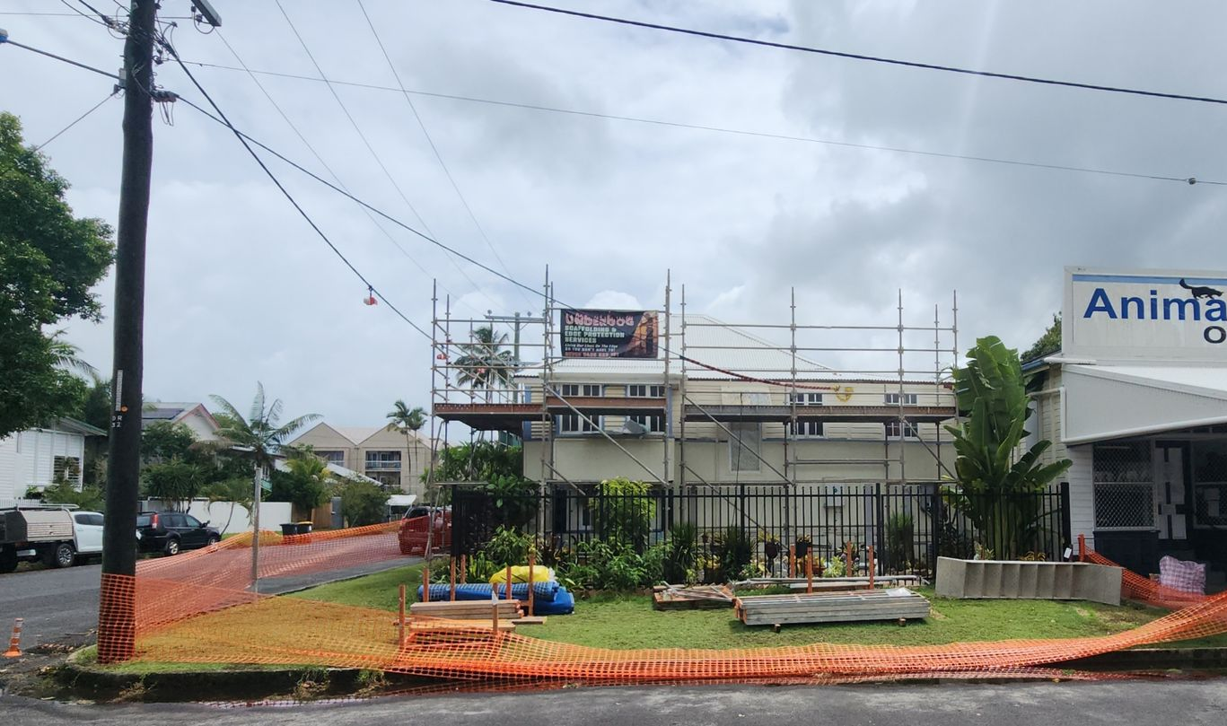 Roundabout with orange landscaping in front of a building under construction on a cloudy street corner — Underdog Edge Protection in Redlynch, QLD