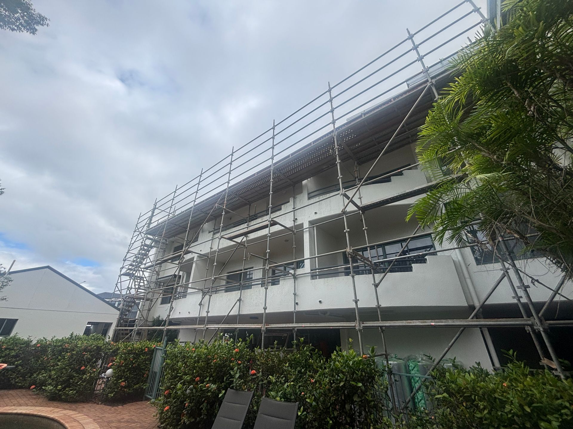 Scaffolding around a white apartment building under construction on a cloudy day — Underdog Edge Protection in Redlynch, QLD
