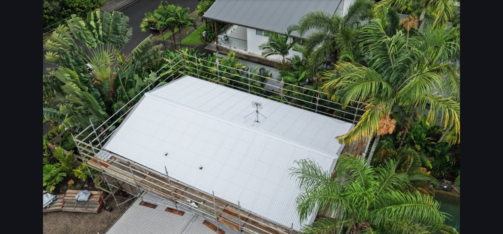 Aerial view of a white-roofed house surrounded by lush green tropical trees and plants — Underdog Edge Protection in Redlynch, QLD