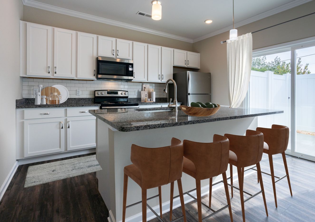 A kitchen with white cabinets, granite countertops, stainless steel appliances, and a large island.