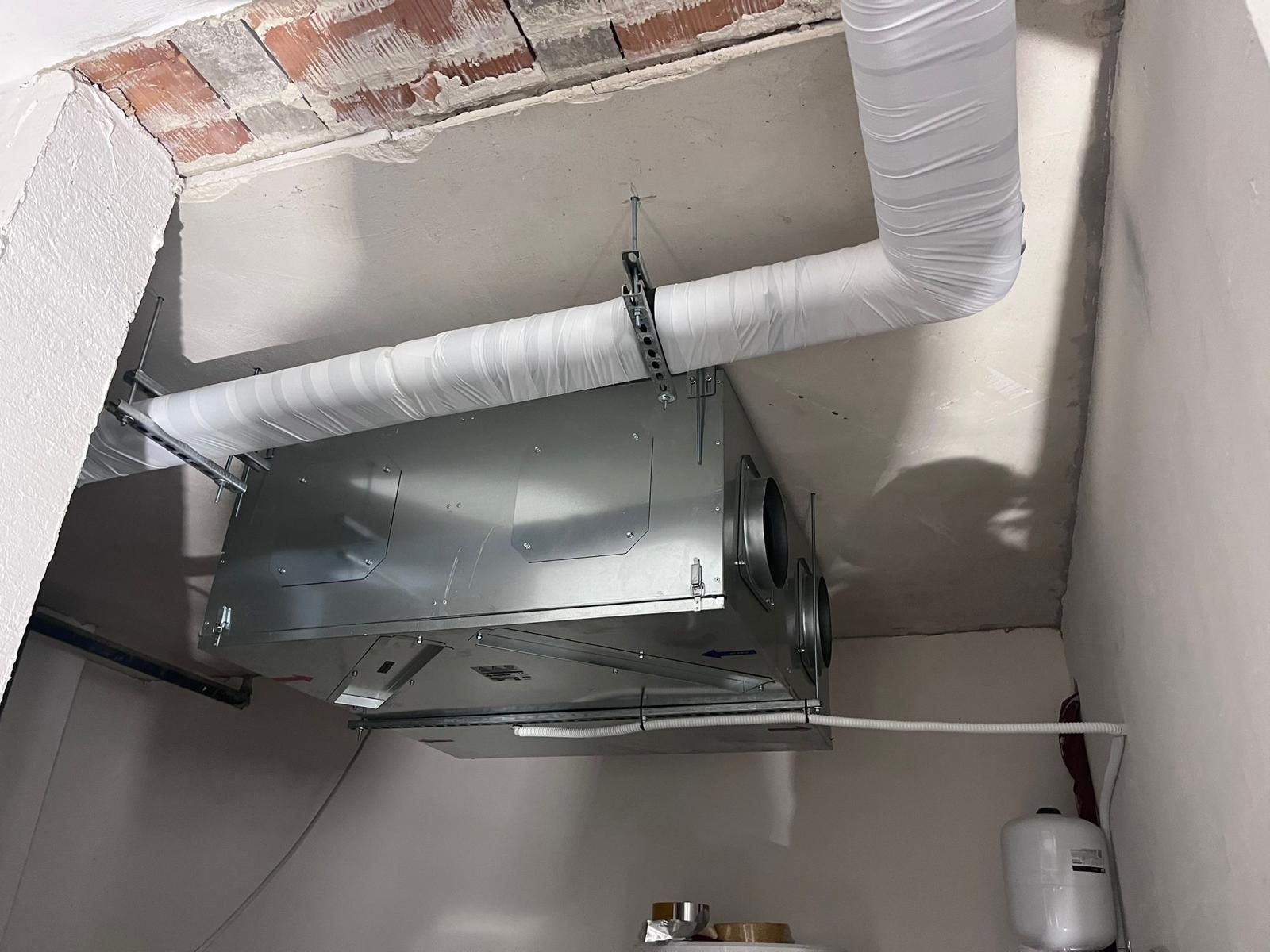 Un'unità HVAC rettangolare sospesa al soffitto, collegata a un condotto flessibile.