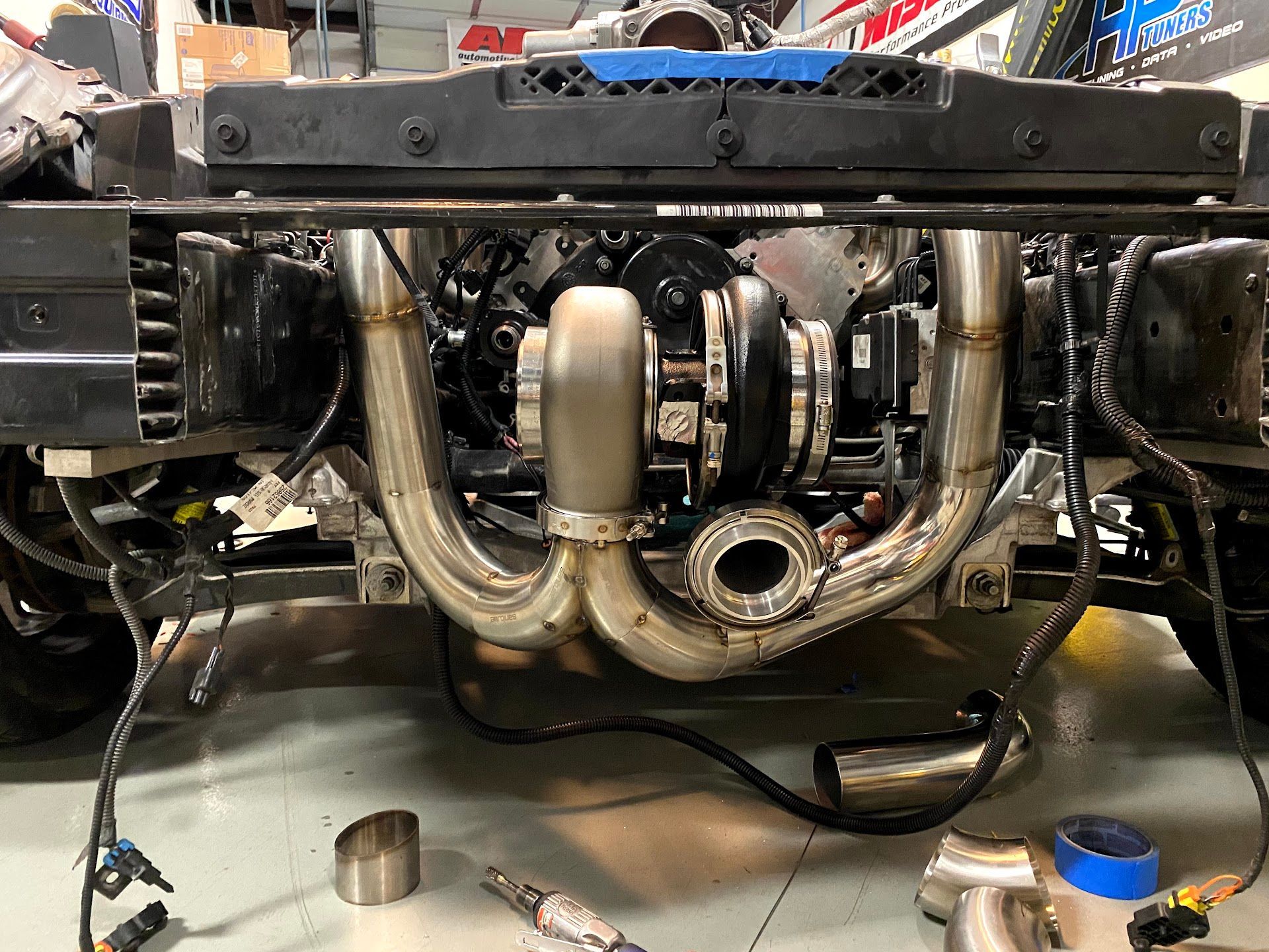 Car engine with a large turbocharger, stainless steel pipes, and front end components. | YellowHammer Racing