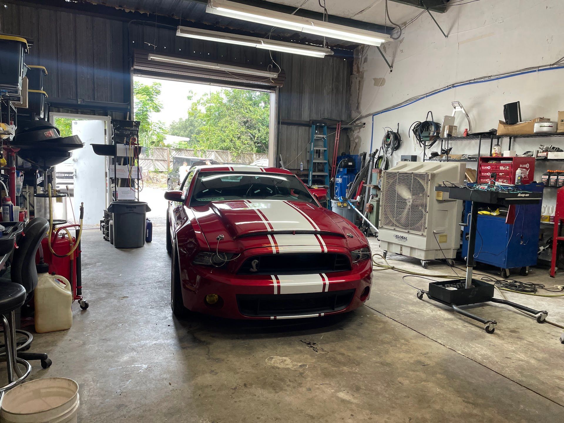 Red and white Mustang in a garage with tools and equipment. | YellowHammer Racing