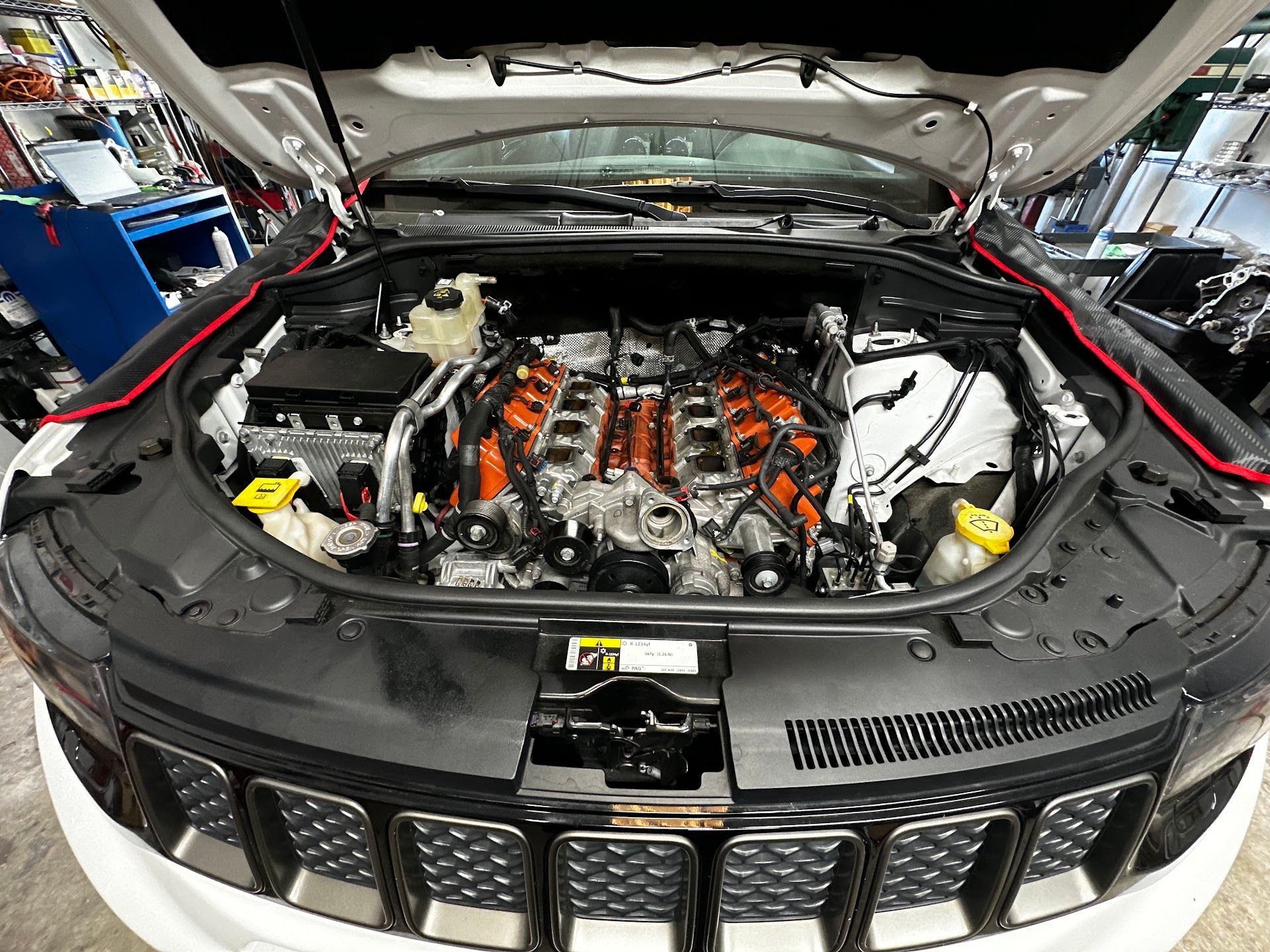 Jeep engine bay with the hood open, showcasing a powerful orange-colored engine. | YellowHammer Racing