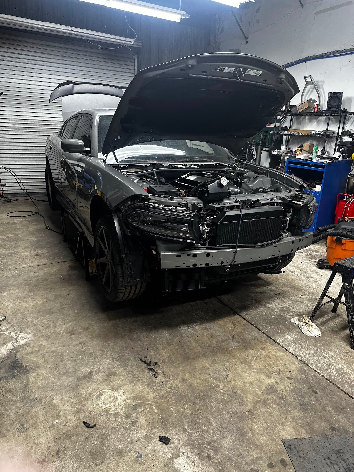Gray Dodge Charger with open hood in a garage, undergoing repair. | YellowHammer Racing