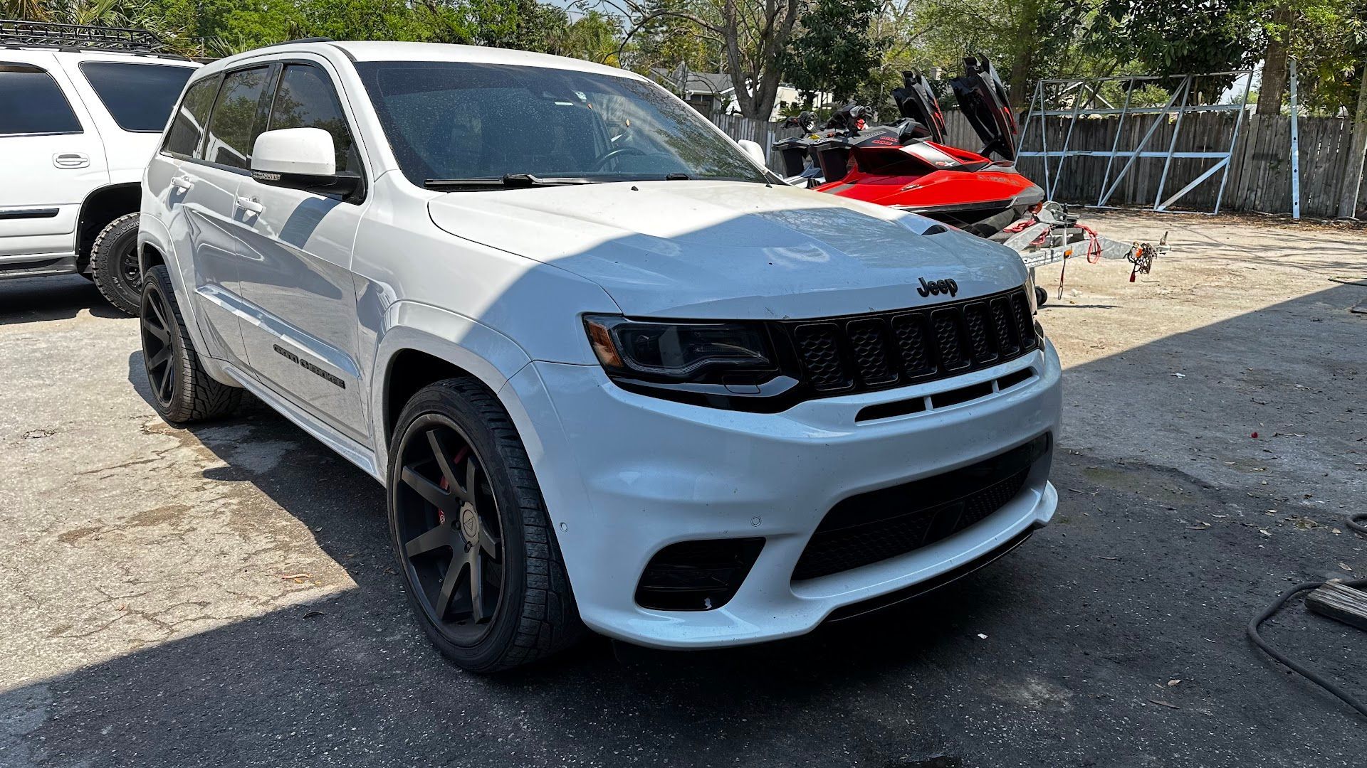 White Jeep Grand Cherokee SUV with black accents parked on a paved lot.