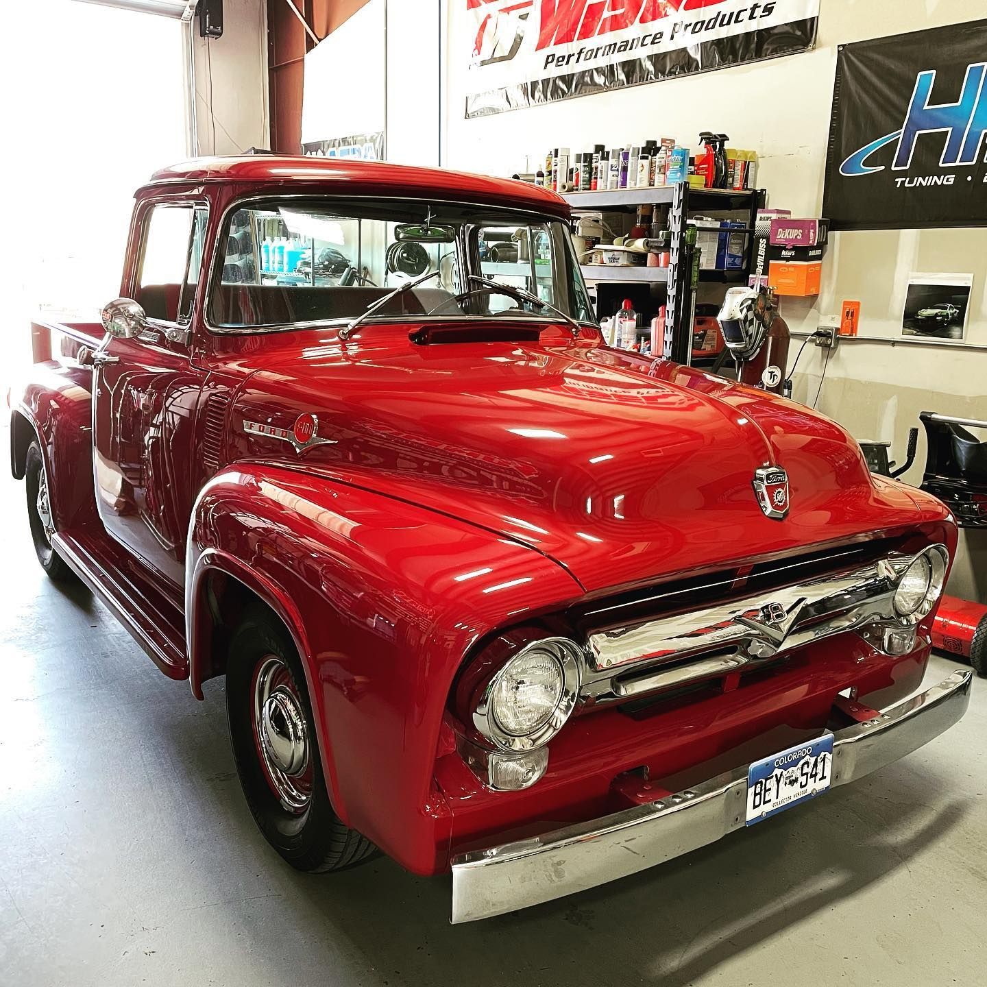 Red vintage Ford pickup truck in a garage, chrome accents, shiny paint. | YellowHammer Racing