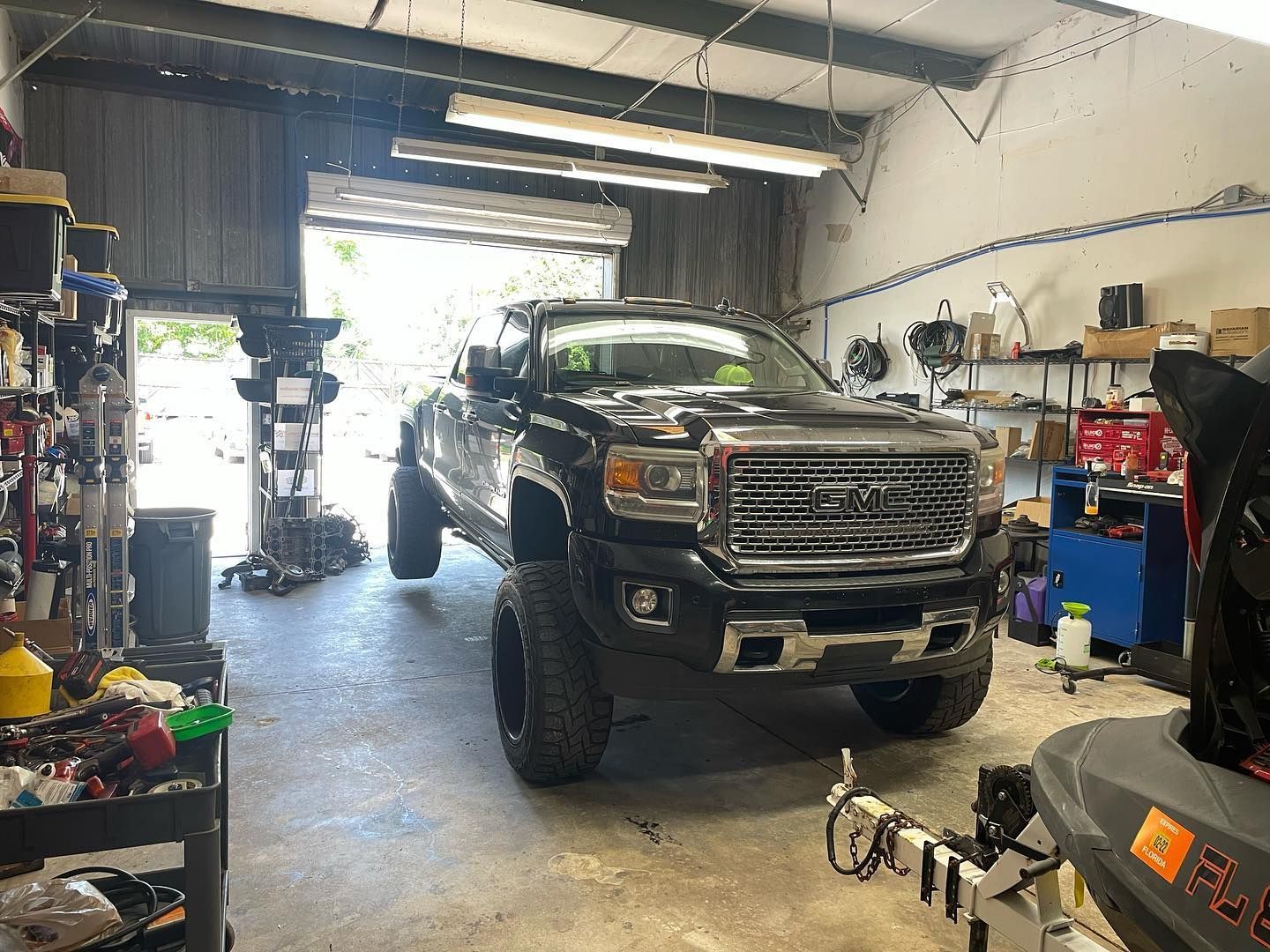 Black lifted GMC truck inside a garage with tools, and jet ski.  | YellowHammer Racing