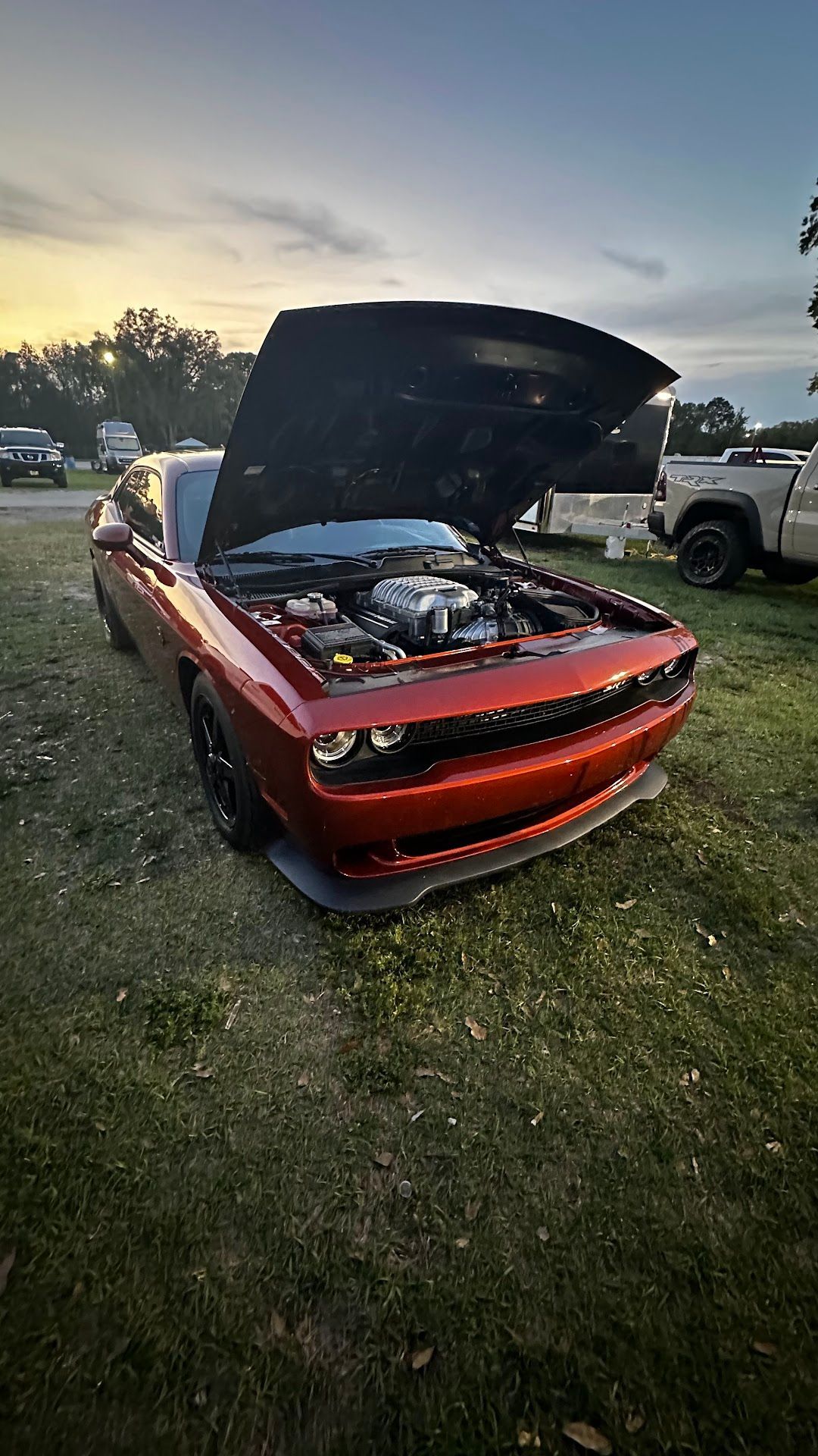 Red Dodge Challenger with open hood on grass, parked outdoors.  | YellowHammer Racing