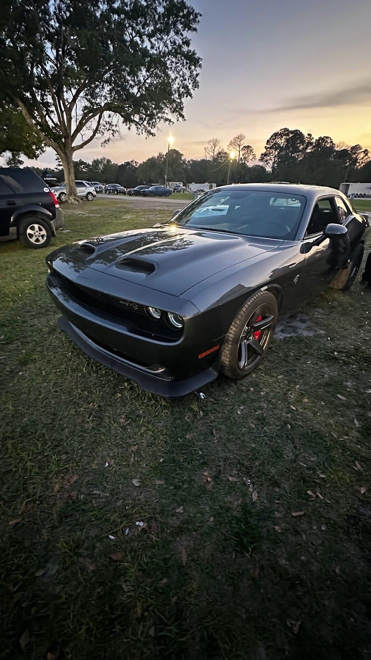 Dark gray Dodge Challenger at a race track, sunset in the background. | YellowHammer Racing