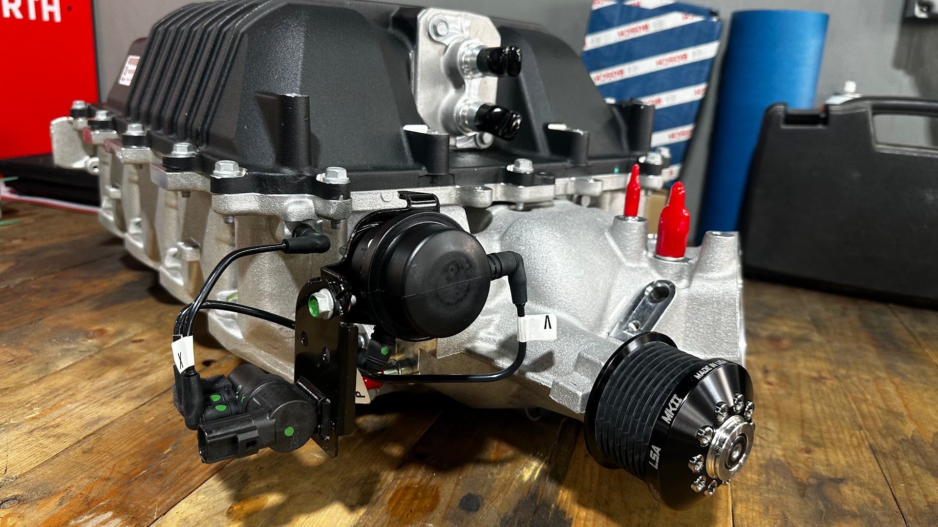 Supercharger assembly on a workbench, black and silver. | YellowHammer Racing