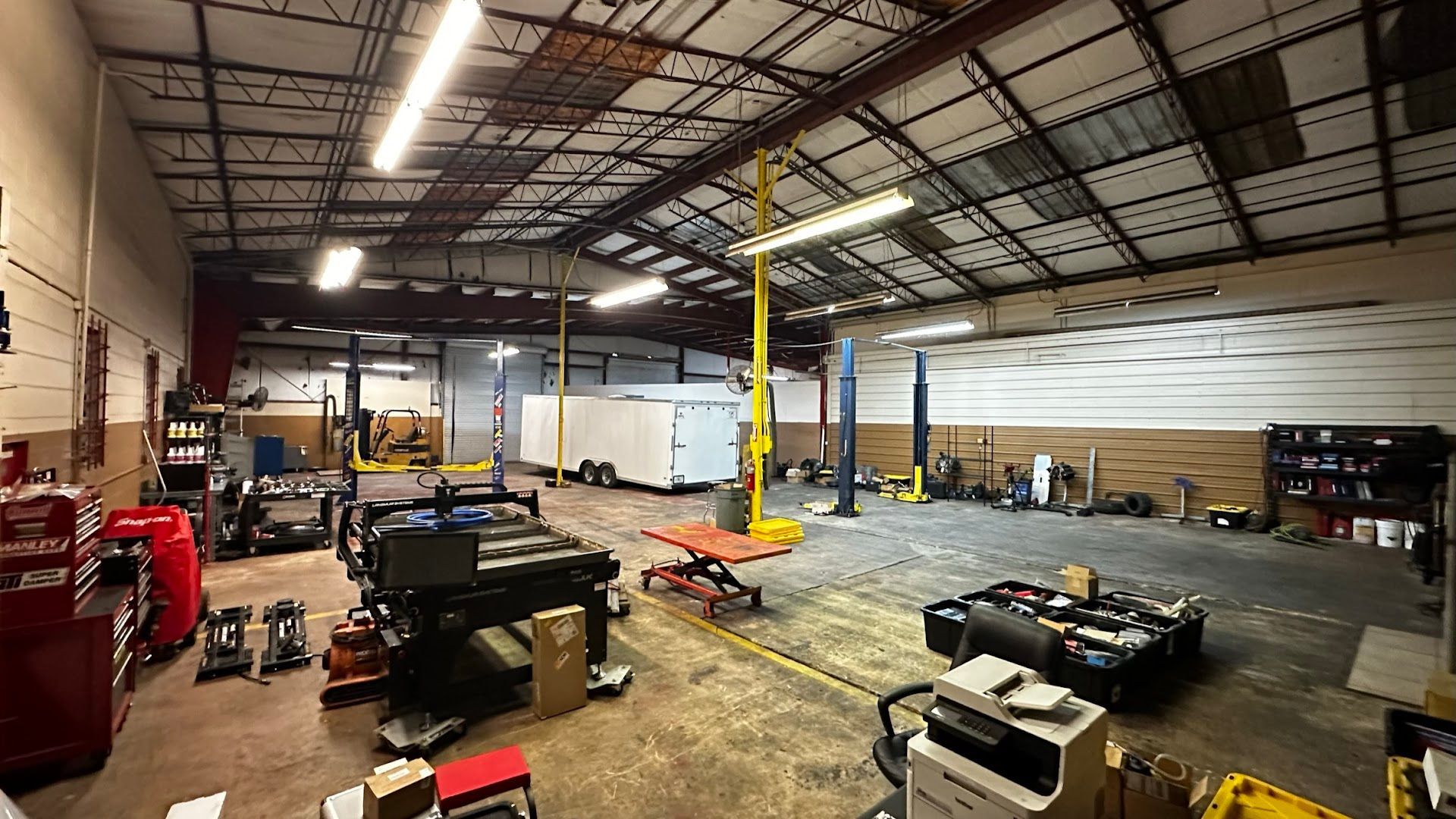 Large auto repair shop interior with vehicles, lifts, tools, and a trailer.  | YellowHammer Racing