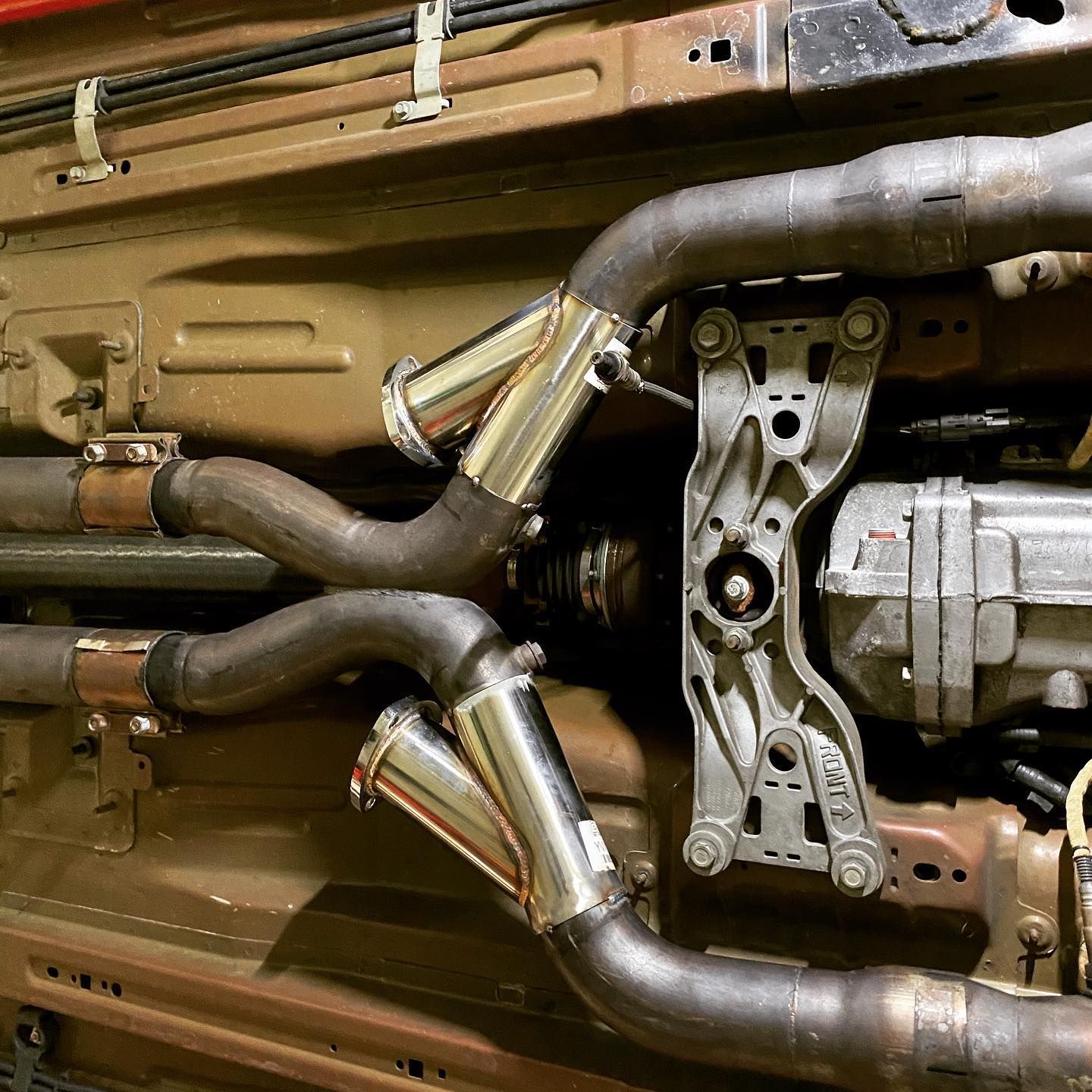 Undercarriage of a vehicle showing exhaust pipes, Y-pipes, mounting bracket, and drive shaft. | YellowHammer Racing
