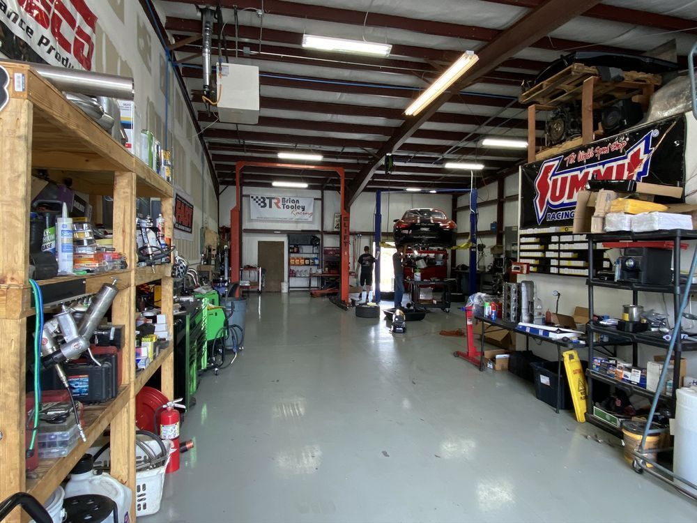 Inside auto repair shop with car on lift, tools, and shelving. | YellowHammer Racing