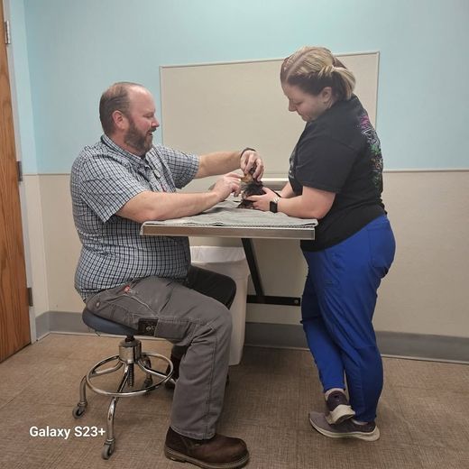 Two people examining a small object at a desk in a clinic room.