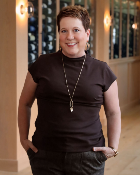 Woman with short brown hair, smiling, wearing a floral blouse.
