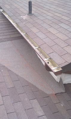 Damaged roof edge with bent metal flashing and a visible gap between shingles