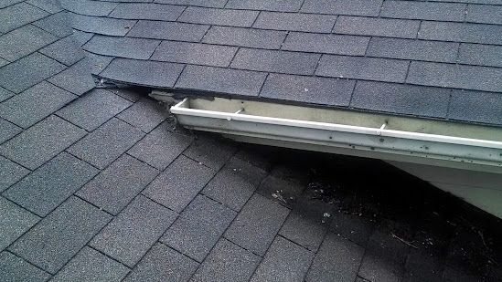 Roof shingles with a damaged ridge vent and a visible gap in the roofing