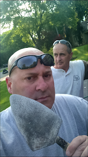 Two men outdoors, one holding a trowel and posing with sunglasses on his head