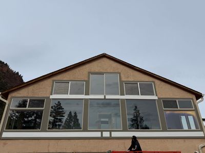 Front view of a house with large windows and a steep gabled roof under an overcast sky