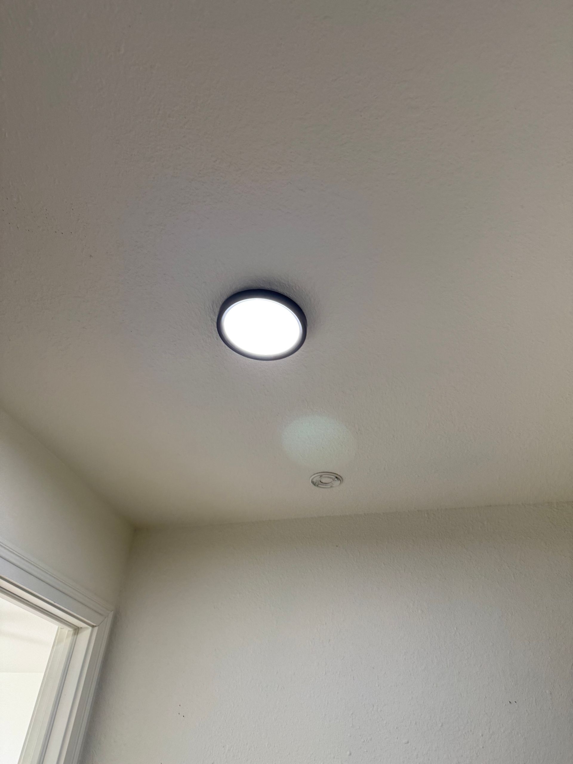 Ceiling light in a plain white room with a window at left.