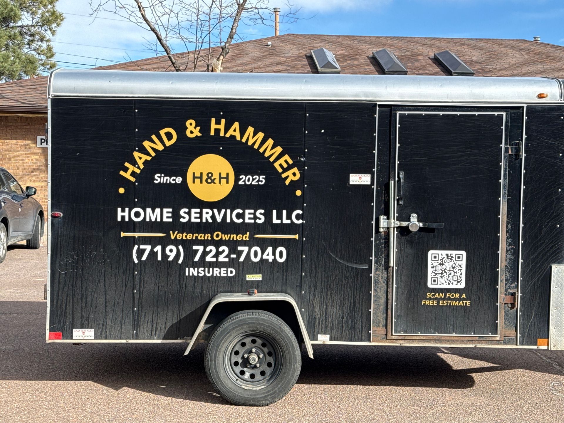 Black Hand & Hammer Home Services LLC trailer with phone number and QR code parked outdoors
