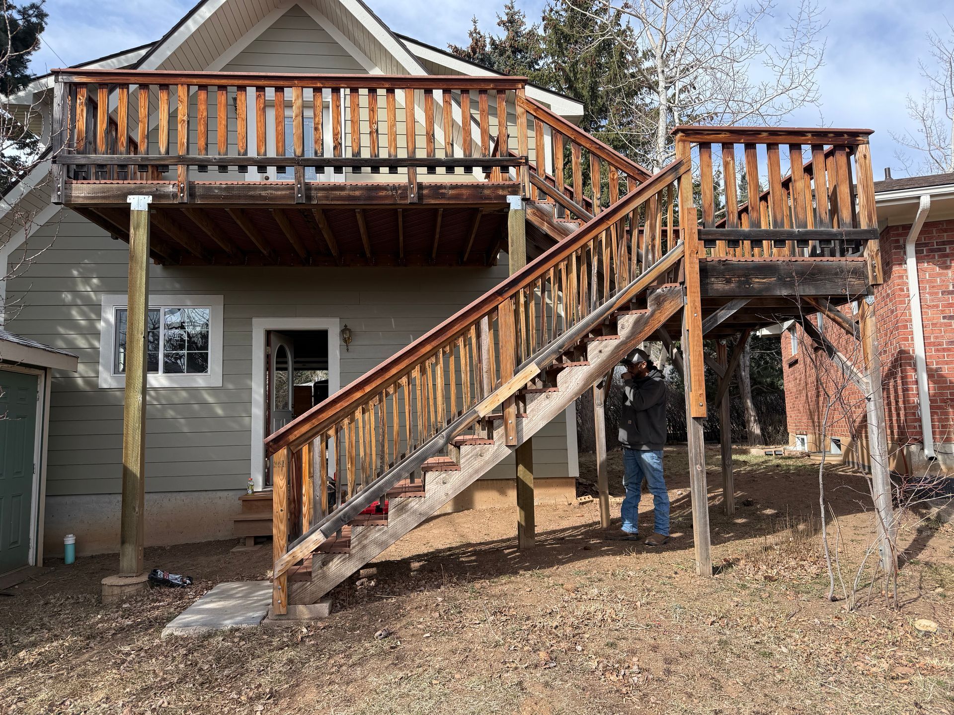 Wooden staircase and deck on a house exterior with a person standing underneath