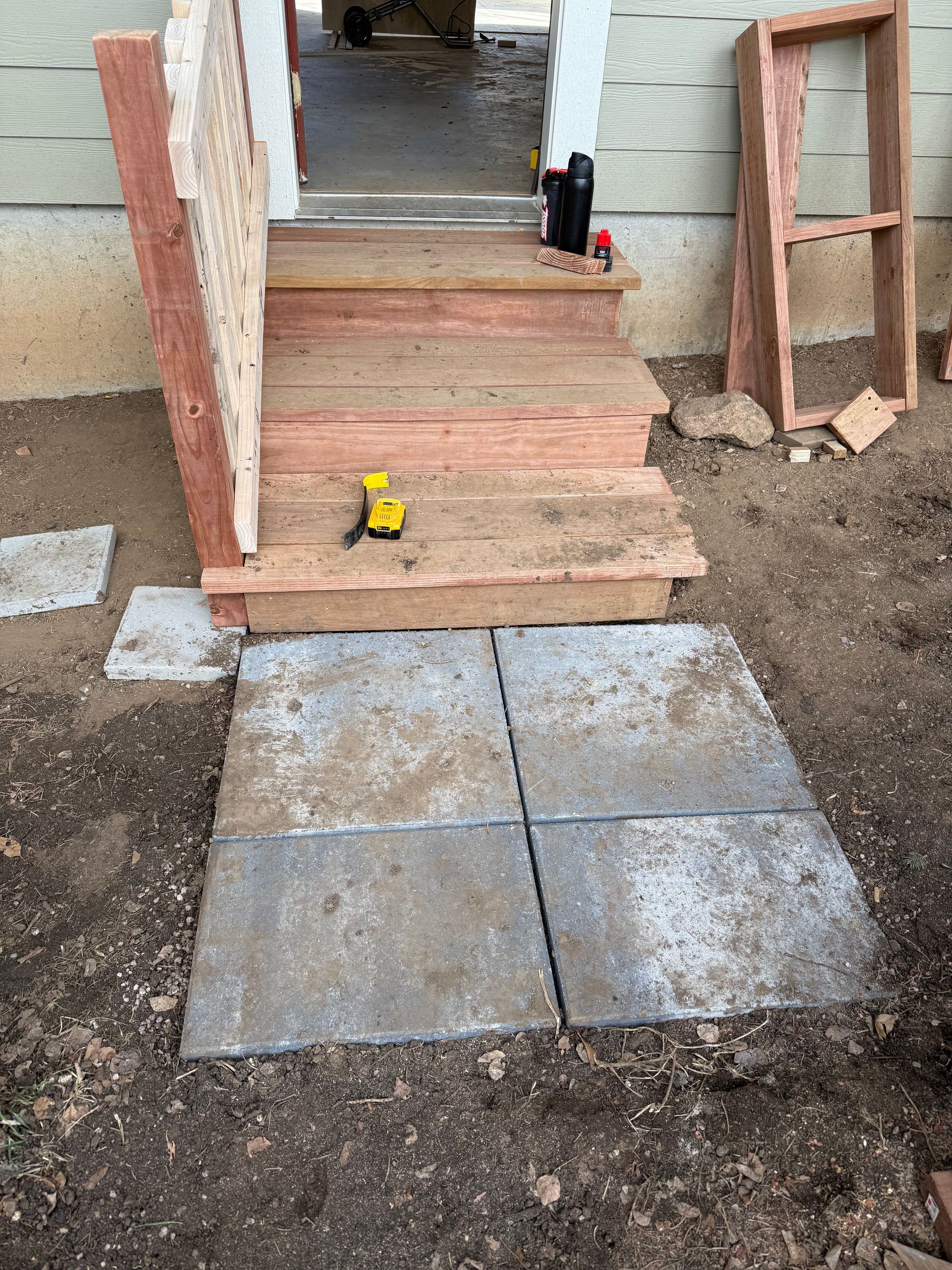 Partially built front porch with unfinished steps, brick sides, and a yellow tape measure on the landing