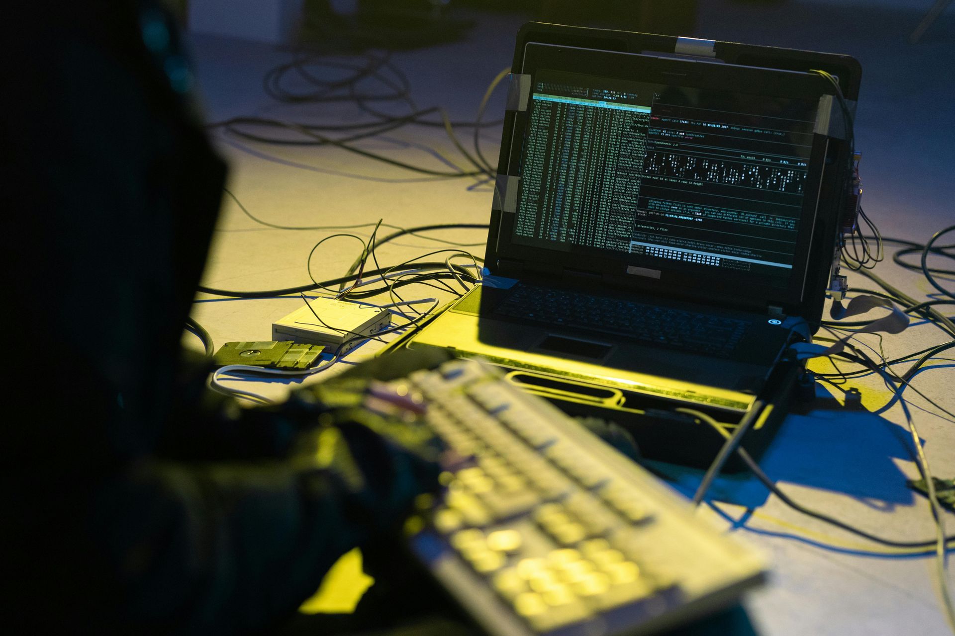 A person is typing on a keyboard next to a laptop