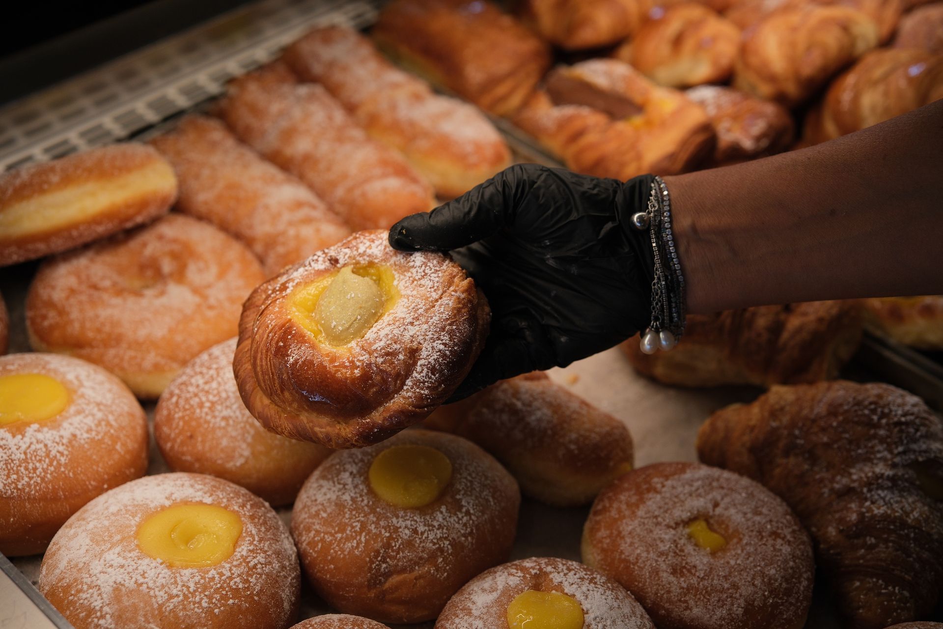 dolce ripieno di crema pasticcera, preso da un vassoio di prodotti da forno in una panetteria.