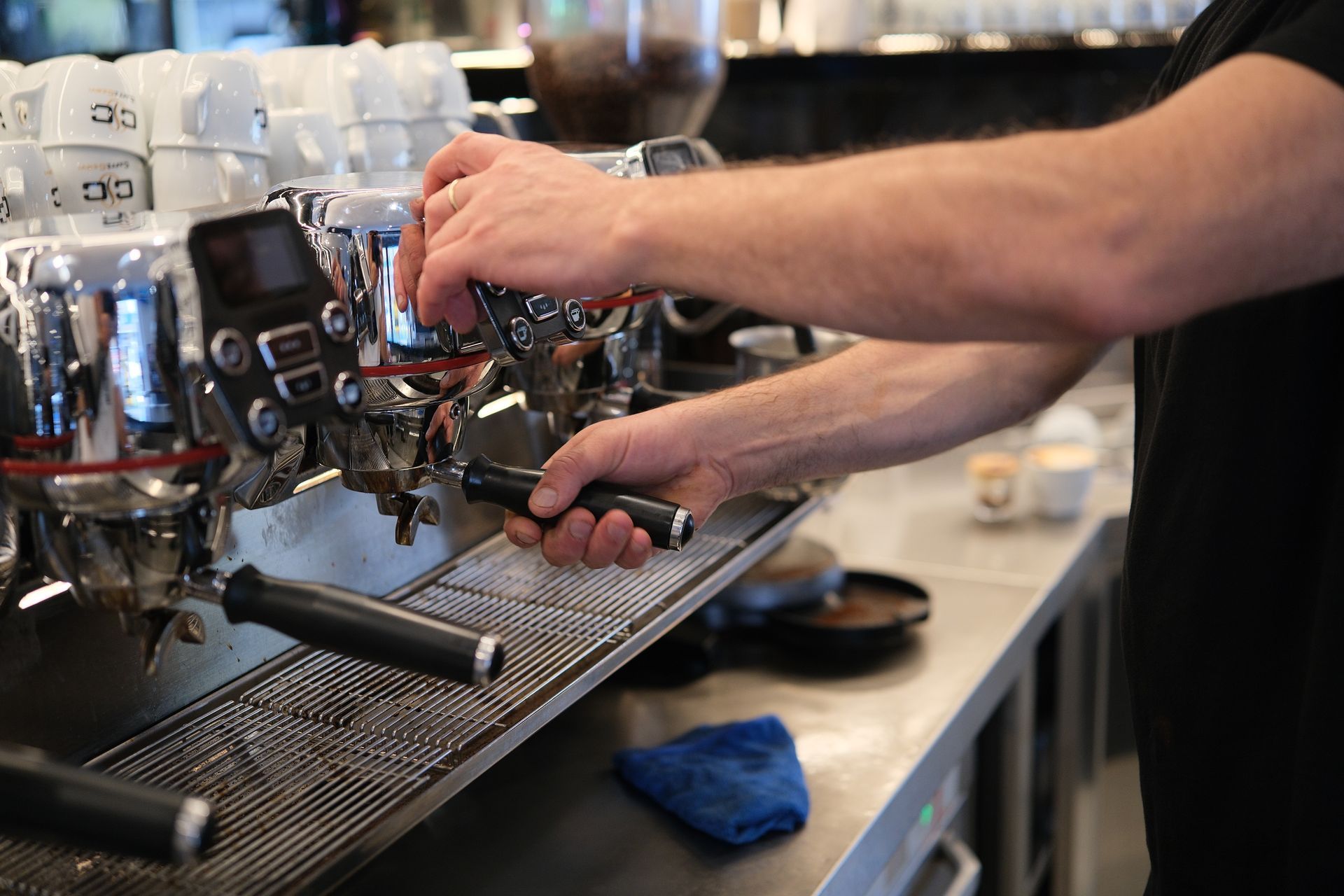 Barista che usa una macchina per l'espresso in un bar, preparando un caffè.