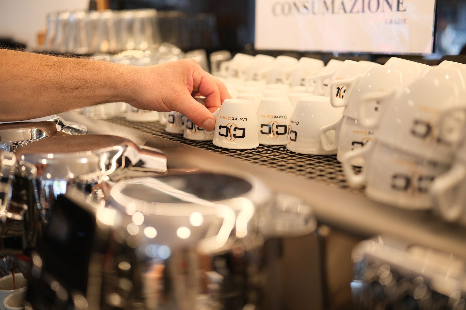 Mano che prende una tazzina dalla pila di una macchina per il caffè.