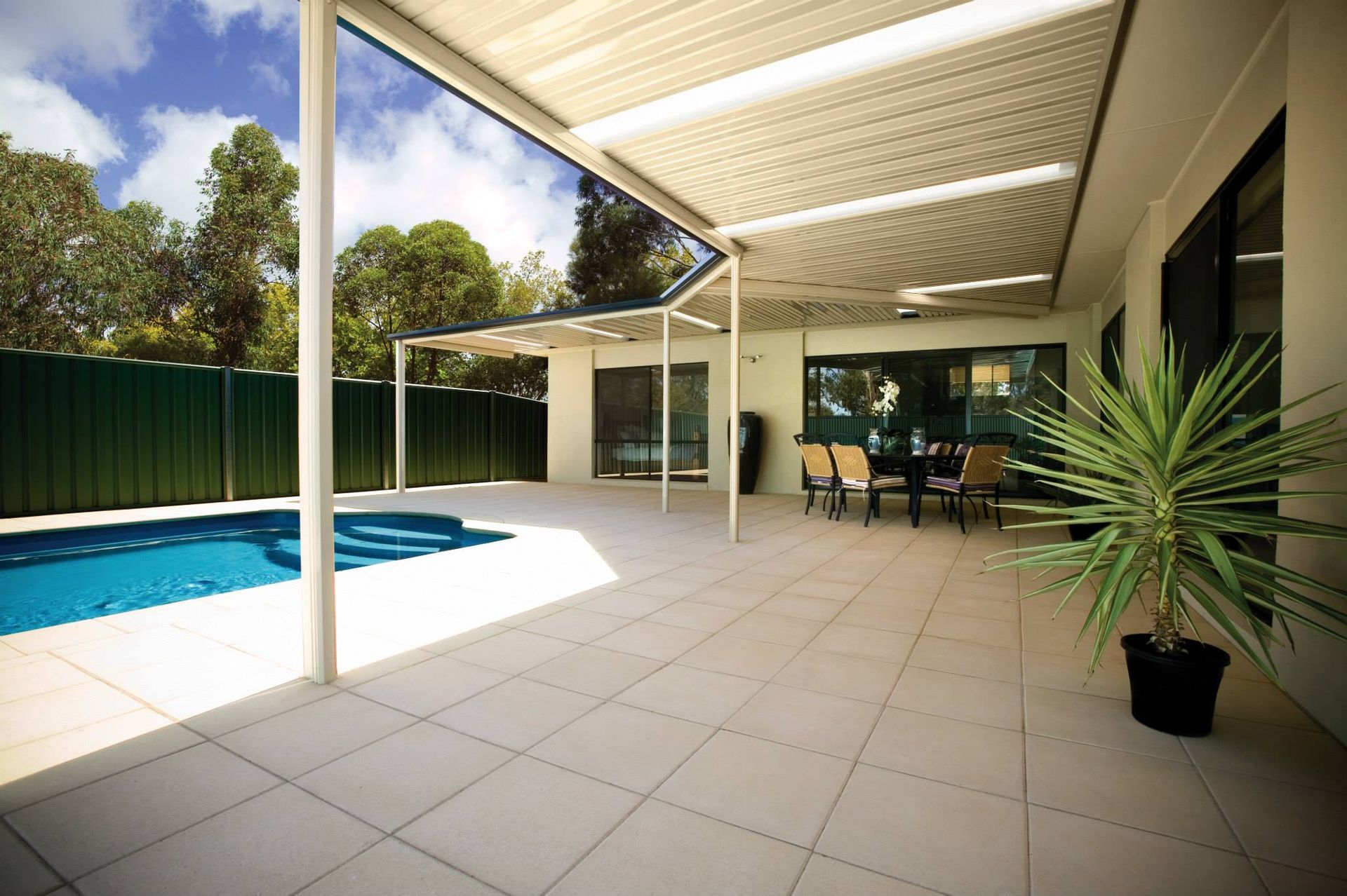 A patio with a table and chairs next to a pool
