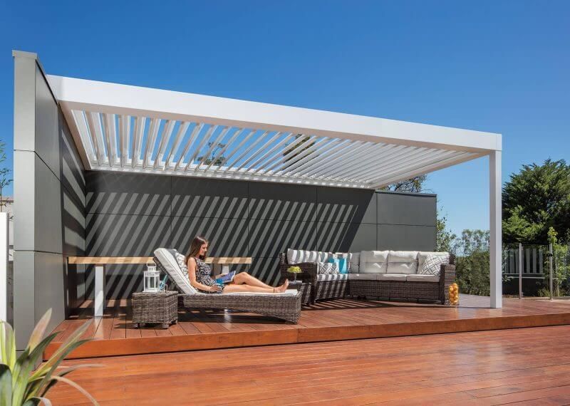 A woman is laying on a lounge chair under a pergola.