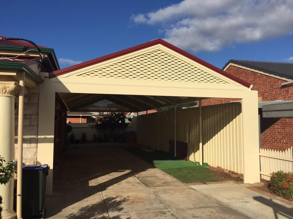 A white carport with a red roof is in front of a house.