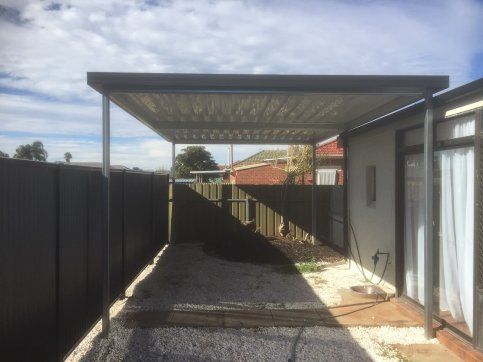There is a carport in the backyard of a house.