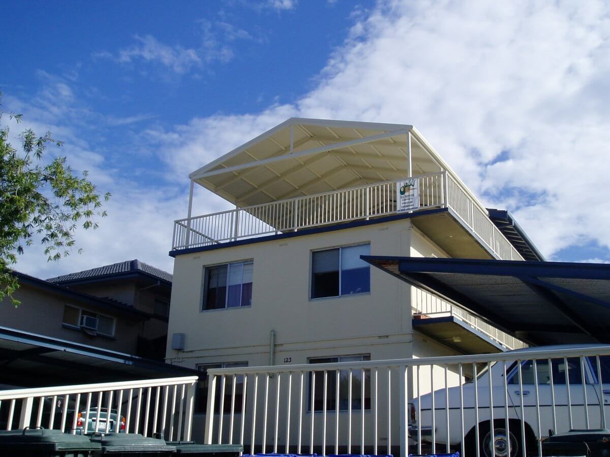A white van is parked in front of a house with a balcony