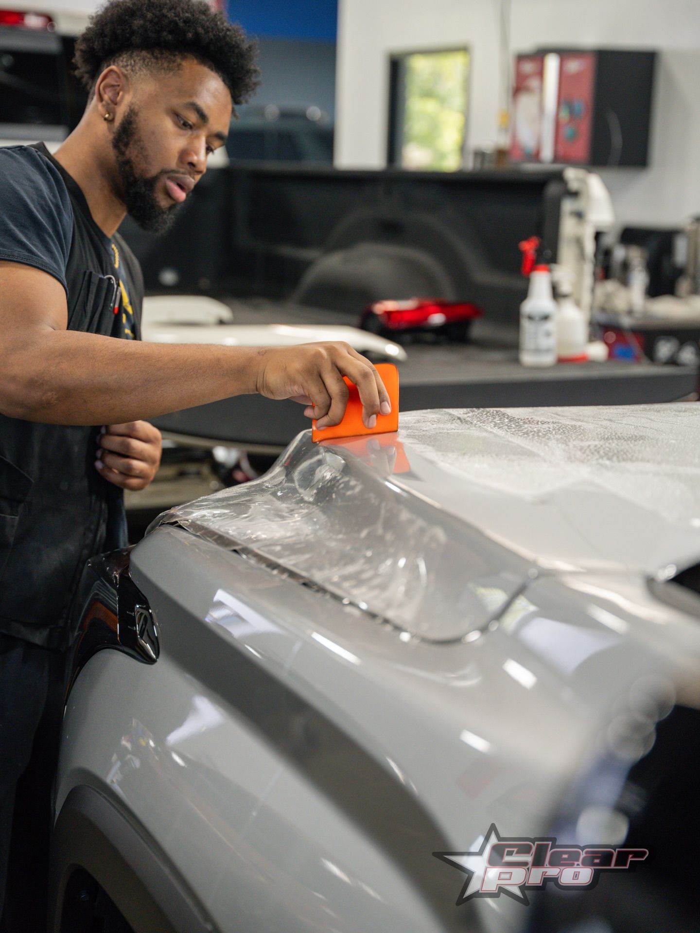 Detailing a gray car with a squeegee in a workshop