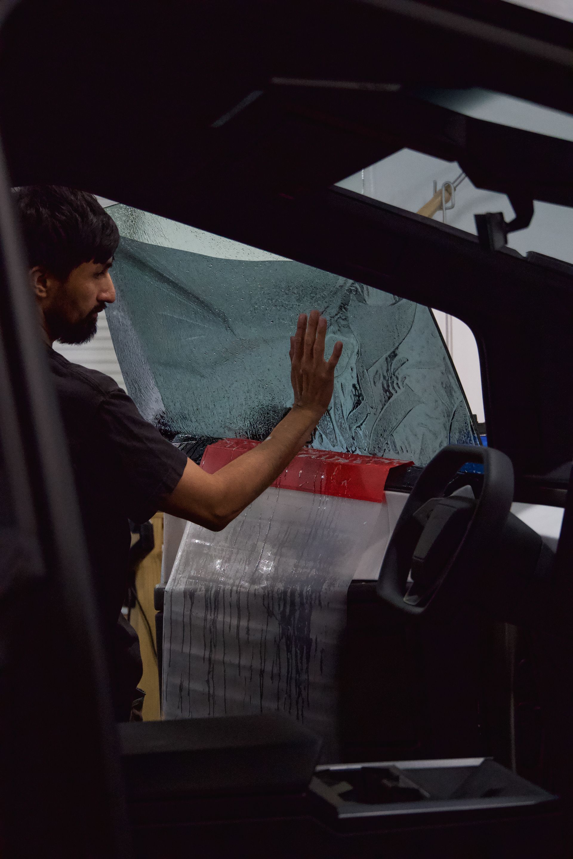 A man is applying tinted windows to a car window.